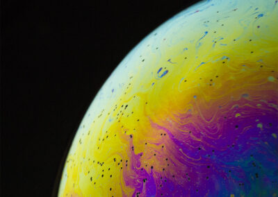 The planetlike surface of an iridescent bubble on a black background