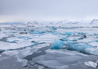 Large chunks of ice in pond with foggy hills in background