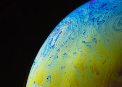 The planetlike surface of an iridescent bubble on a black background