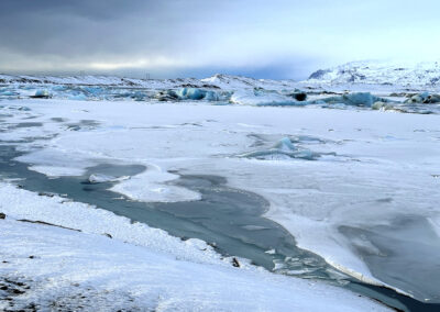 Snowy Icelandic pond with ice and foggy hills