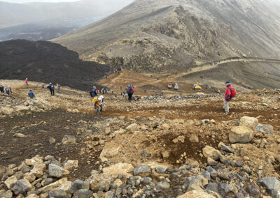Visitors scramble across the rocks in a volcanic landscape
