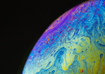 The planetlike surface of an iridescent bubble on a black background