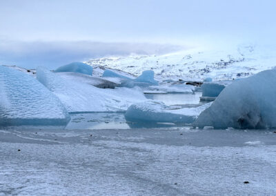 Large chunks of ice in pool with foggy hills in background