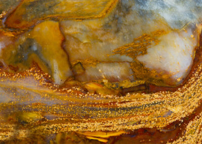 A stream of yellow nodules flows around a lighter iridescent mineral