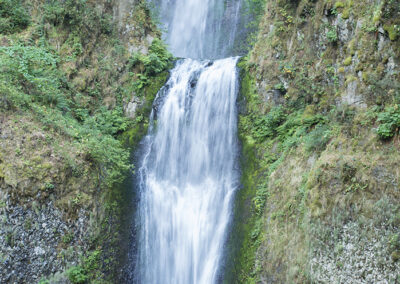 Dramatic vertical photograph of Multnomah Falls in Oregon with viewing bridge