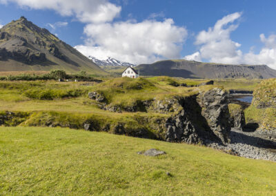 A picturesque landscape with hills and a house at Arnarstapi