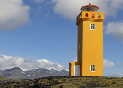 An orange lighthouse dominates an Icelandic coastline