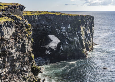 A rocky coastline with a tunnel formation at Svortuloft, Iceland