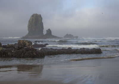 Misty photo of Cannon Beach in Oregon with jutting rocks