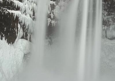 Icelandic waterfall with icicles and visitors in foreground