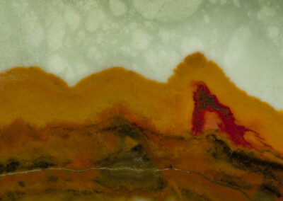 A green sky hangs over orange and red mountains with a reflective lake