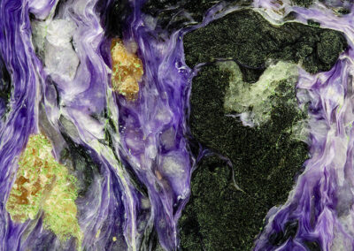 Mineral with green and yellow nodules surrounded by swirling bright purple strands