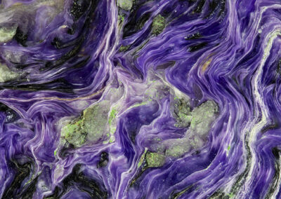 Mineral with green nodules surrounded by swirling bright purple strands