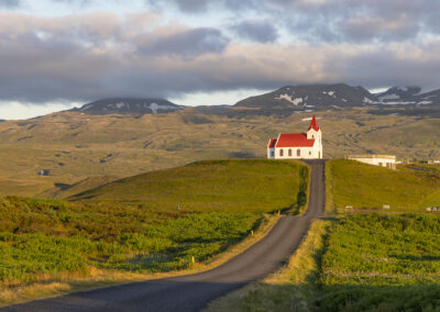 A road to a church bisects the Icelandic countryside