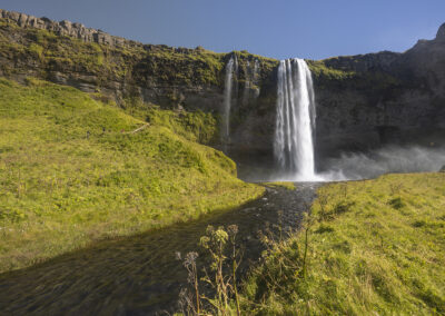 Seljalandsfoss waterfall and river through grassy hills