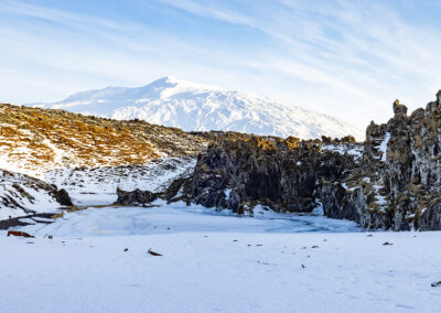 Rocky outcrops and a plain of snow with a distant snowy mountain