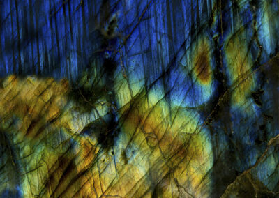 Mineral cross section featuring a cross-grained pattern with orange, greens and blues