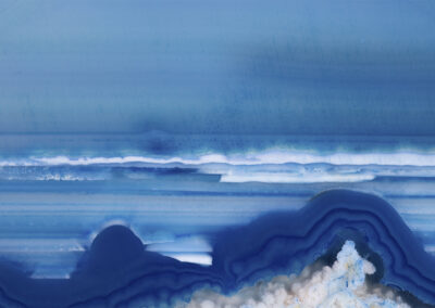A blue and white mineral cross section resembling a shoreline seascape