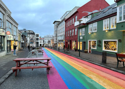 A rainbow-painted street lined with shops and houses
