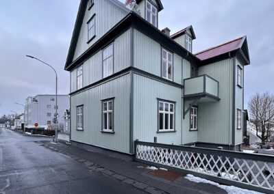 A green house stands apart on an Icelandic street