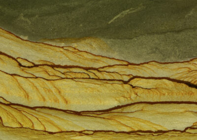 Mineral veins resembling sand dunes under a gray-green sky