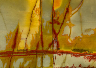 Flamelike red and orange patterns form around darker cracks in a mineral