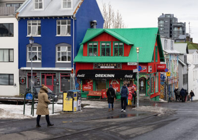 A red building with bright green roof stands out on an Icelandic street