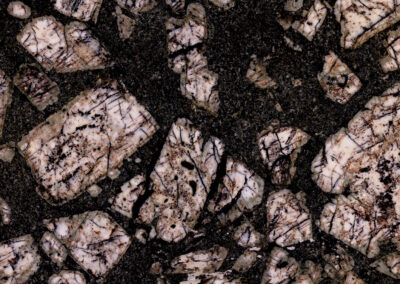 Blocklike peach and white mineral intrusions in a dark matrix