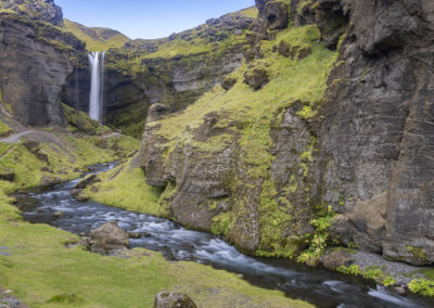 A waterfall and river in a green Icelandic valley