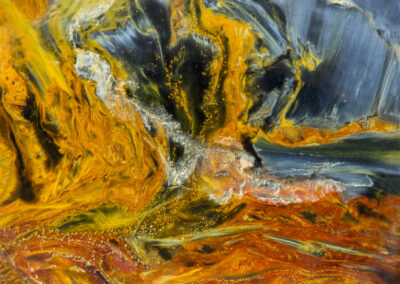 Cloudlike swirls of yellow and rust flow through a prussian blue mineral background