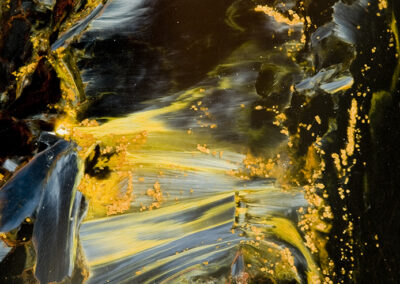 Mineral formations in yellow, blue and black form patterns that are crystalline, stringy and dappled