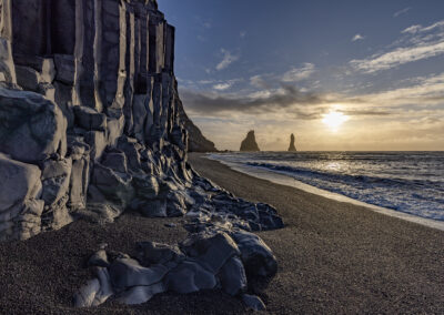 Black beach scene with rocky promontories near sunset