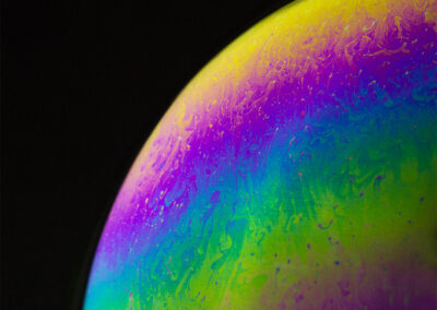 The planetlike surface of an iridescent bubble on a black background